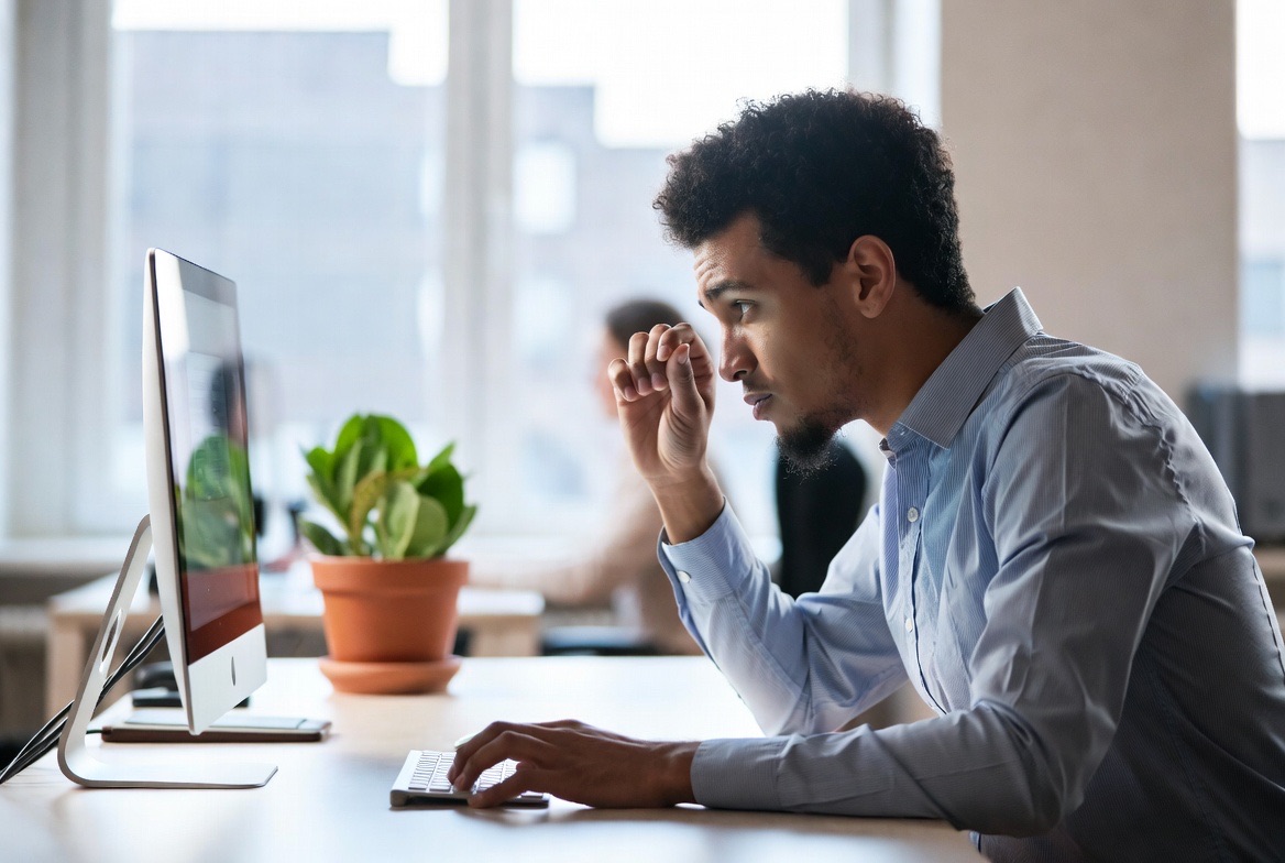 A professional working on a laptop at a tidy desk with a plant