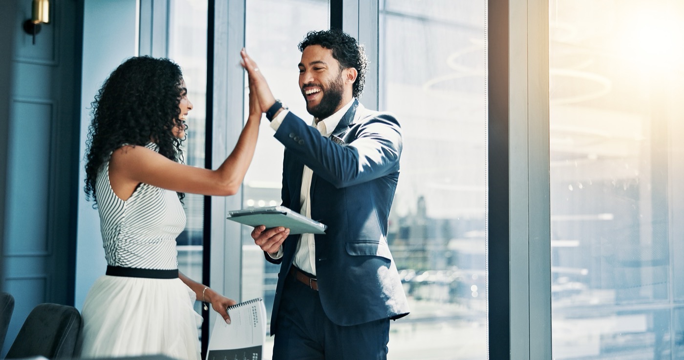 Two colleagues celebrating with a high-five by a window