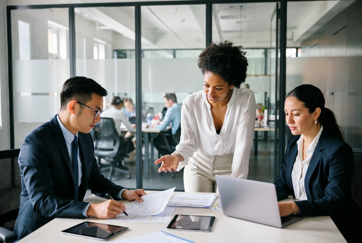 A compliance team collaborating over laptops in an open office