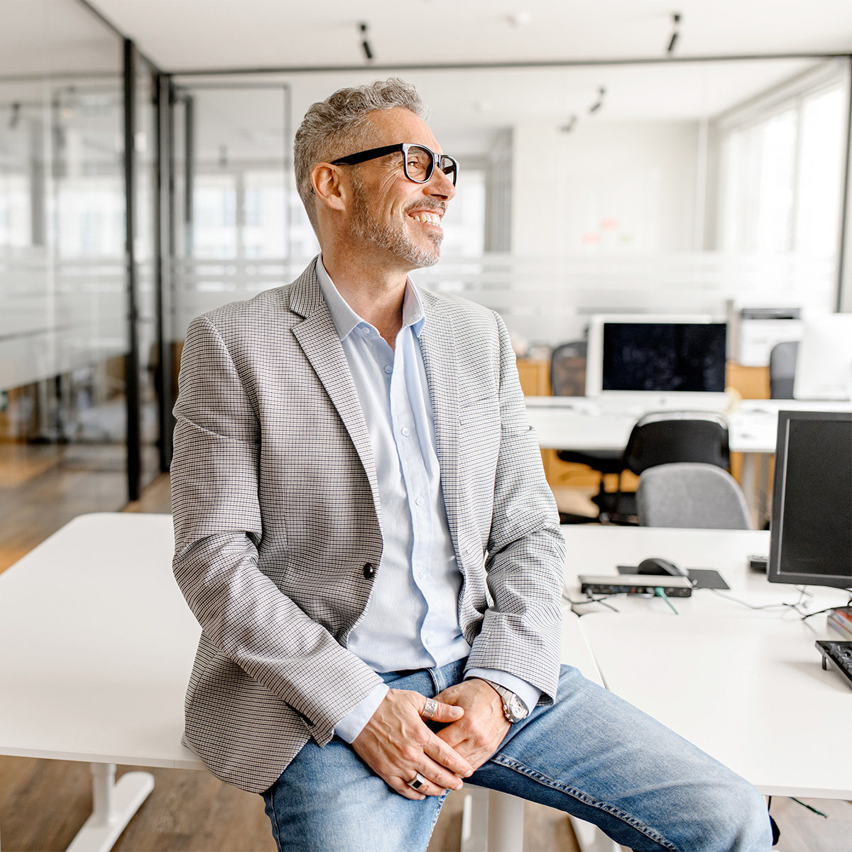 Serene modern middle aged businessman in formal wear leaned on the desk looking away Serene modern middle aged businessman in formal wear leaned on the desk looking away, inspired and calm mature business owner at the office, confident grey-haired man in relaxed pose